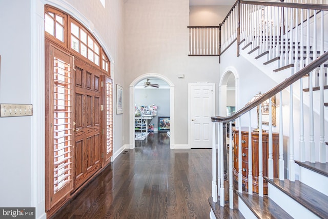 entrance foyer featuring a towering ceiling, ceiling fan, and dark hardwood / wood-style flooring