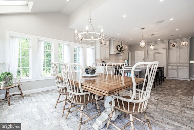 dining space featuring vaulted ceiling with skylight and a notable chandelier