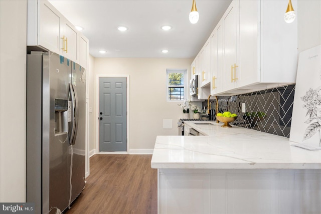 kitchen with light stone counters, white cabinetry, appliances with stainless steel finishes, pendant lighting, and hardwood / wood-style flooring