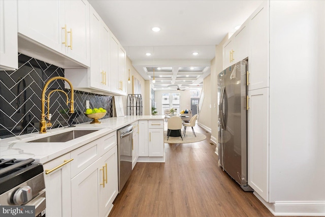 kitchen with stainless steel appliances, white cabinetry, beam ceiling, sink, and hardwood / wood-style floors