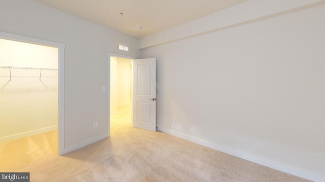 unfurnished bedroom featuring light carpet, a spacious closet, and a closet