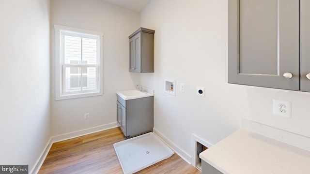 laundry area featuring sink, electric dryer hookup, cabinets, washer hookup, and light hardwood / wood-style floors