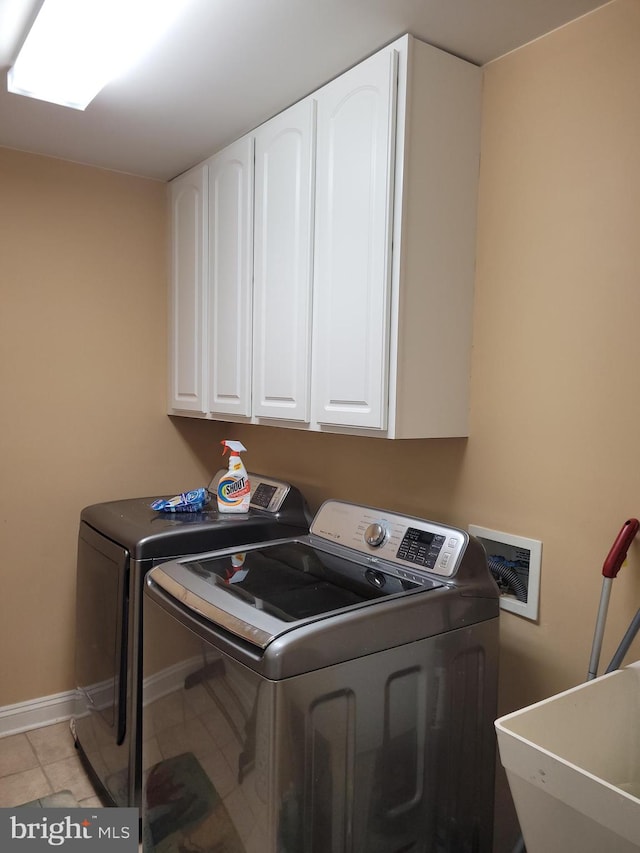 washroom featuring sink, washer and dryer, light tile patterned floors, and cabinets