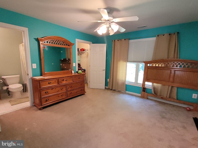 carpeted bedroom with a spacious closet, ensuite bathroom, a closet, and ceiling fan