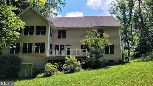 back of property featuring a deck and a lawn