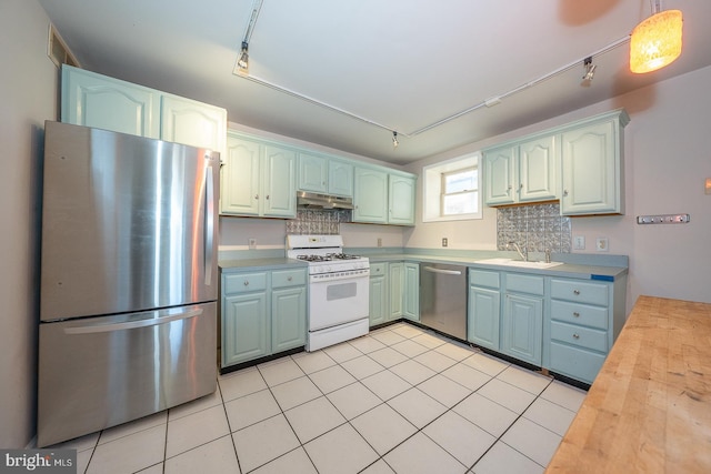 kitchen featuring stainless steel appliances, track lighting, sink, tasteful backsplash, and decorative light fixtures