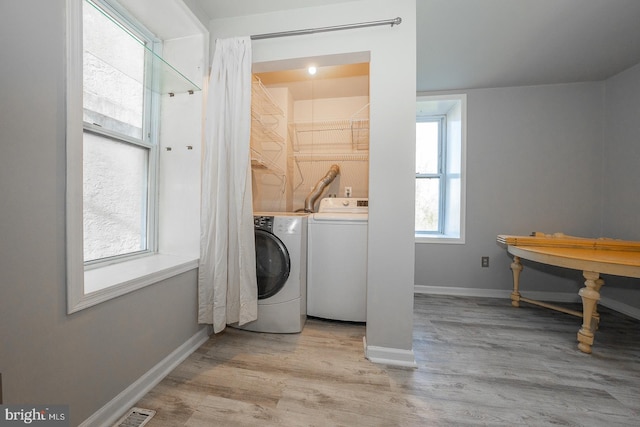 laundry room with washing machine and clothes dryer and light hardwood / wood-style floors