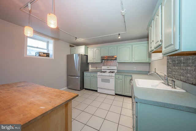 kitchen featuring stainless steel refrigerator, pendant lighting, sink, rail lighting, and white gas stove