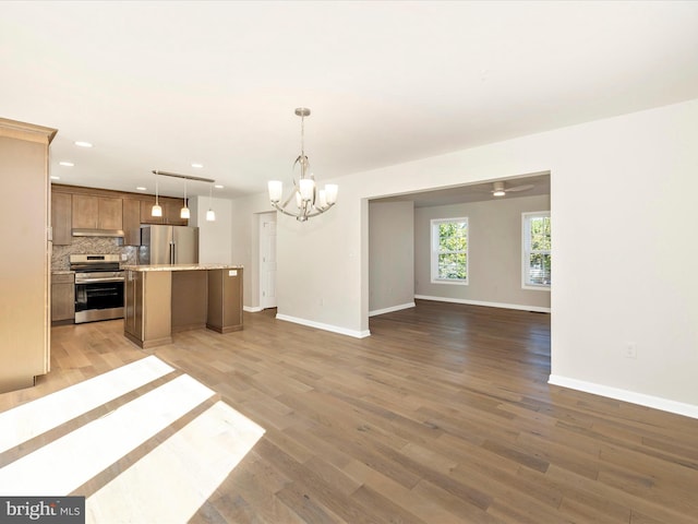 kitchen with a kitchen island, appliances with stainless steel finishes, hanging light fixtures, and wood-type flooring