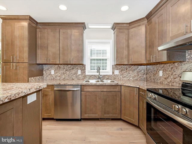 kitchen featuring decorative backsplash, stainless steel appliances, sink, light stone counters, and light hardwood / wood-style floors