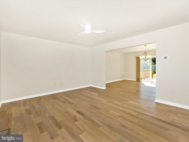 spare room with ceiling fan with notable chandelier and hardwood / wood-style floors