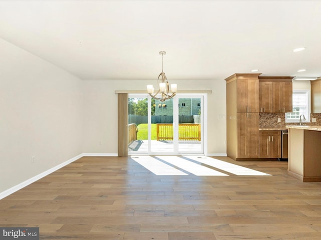 unfurnished dining area featuring an inviting chandelier and light wood-type flooring