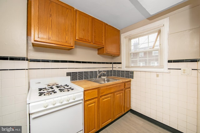 kitchen featuring tile walls, white range oven, and sink