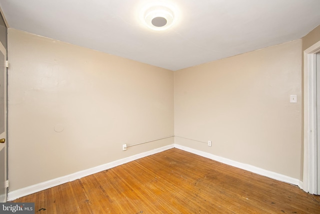 empty room with wood-type flooring and baseboards