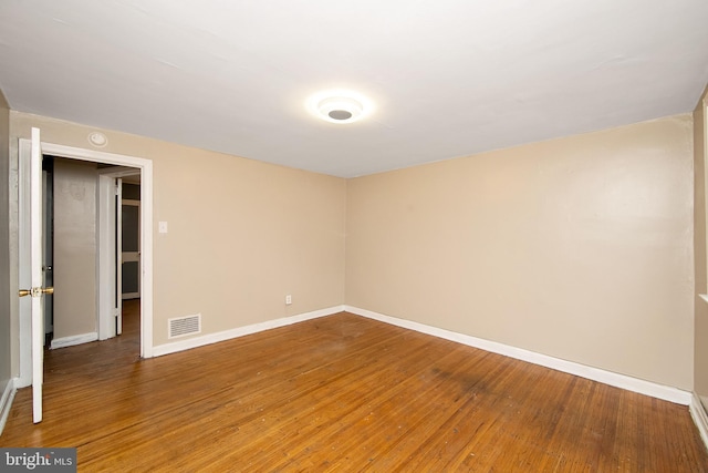 empty room with baseboards, visible vents, and wood finished floors
