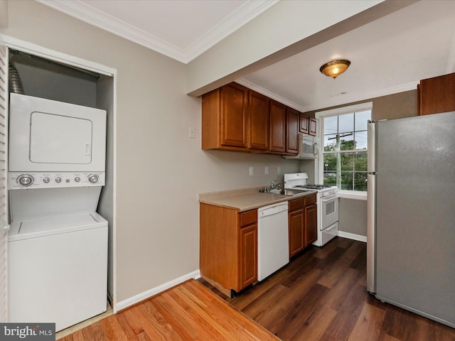 kitchen featuring dark hardwood / wood-style flooring, stacked washing maching and dryer, sink, crown molding, and stainless steel appliances