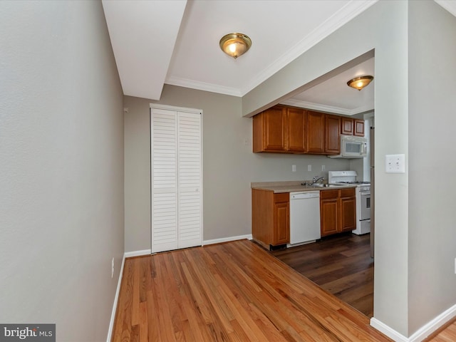 kitchen featuring white appliances, ornamental molding, dark hardwood / wood-style flooring, and sink