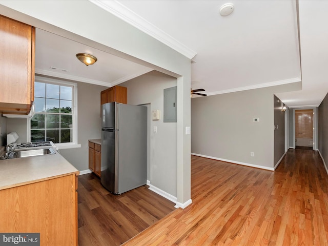 kitchen with ornamental molding, hardwood / wood-style floors, sink, electric panel, and stainless steel refrigerator