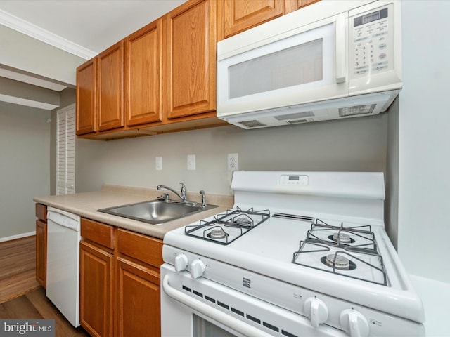 kitchen featuring ornamental molding, sink, hardwood / wood-style floors, and white appliances