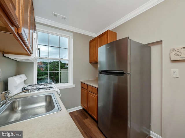 kitchen with stainless steel fridge, dark hardwood / wood-style floors, gas range gas stove, crown molding, and sink