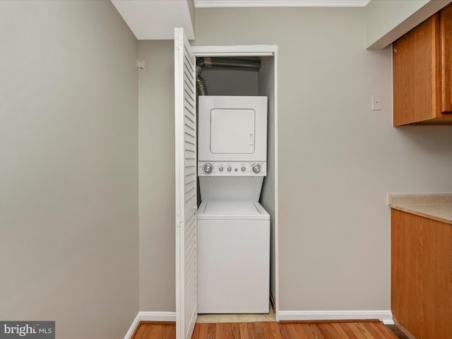 washroom with light hardwood / wood-style floors and stacked washer and clothes dryer