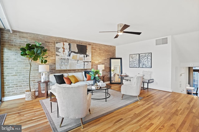 living room with ceiling fan, brick wall, and light hardwood / wood-style flooring