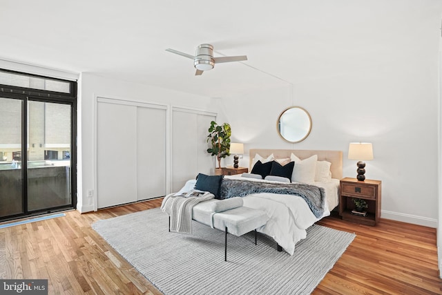 bedroom featuring access to exterior, light hardwood / wood-style floors, ceiling fan, and multiple closets