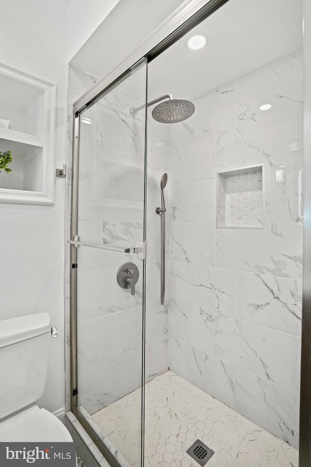 bathroom featuring toilet and a shower with shower door