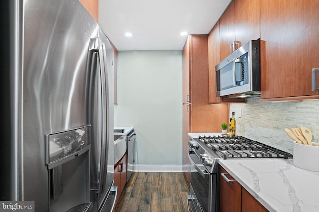 kitchen with decorative backsplash, light stone countertops, dark wood-type flooring, and appliances with stainless steel finishes