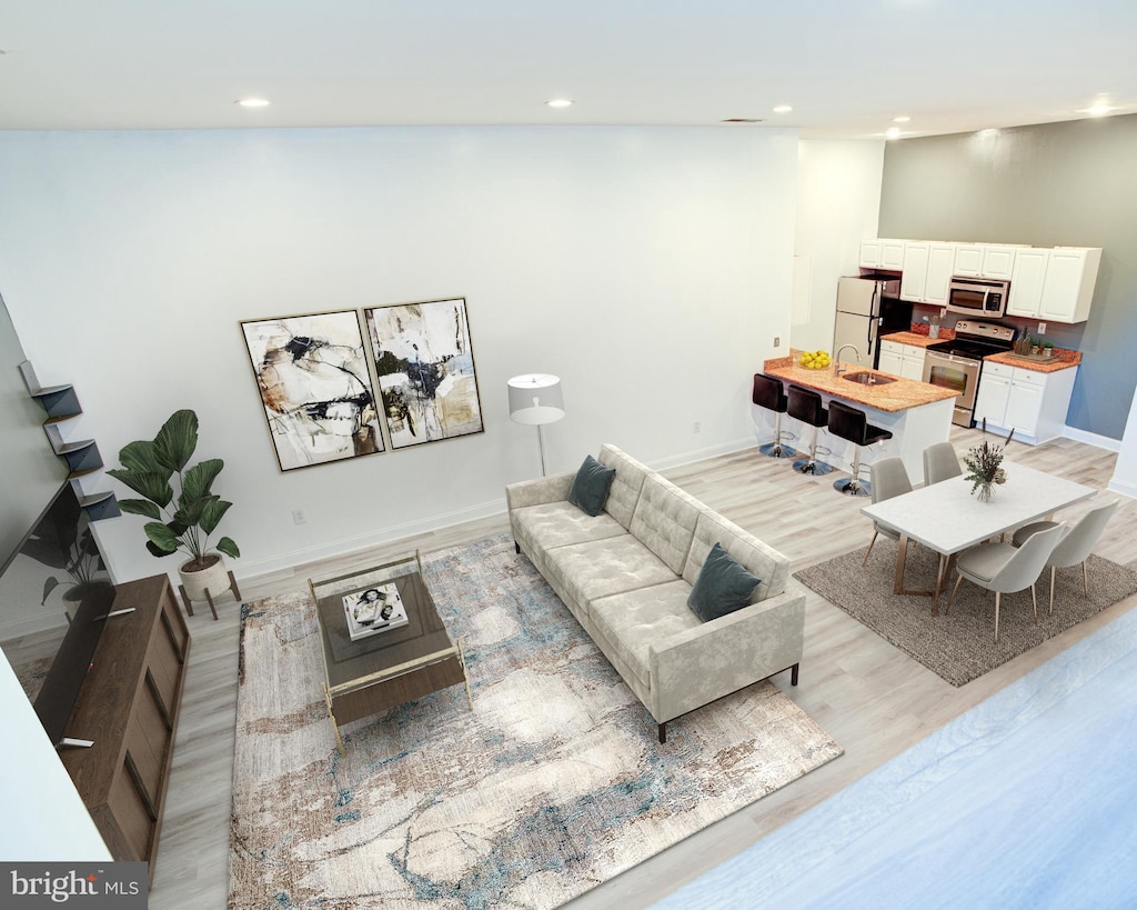 living room featuring vaulted ceiling, light hardwood / wood-style floors, and sink