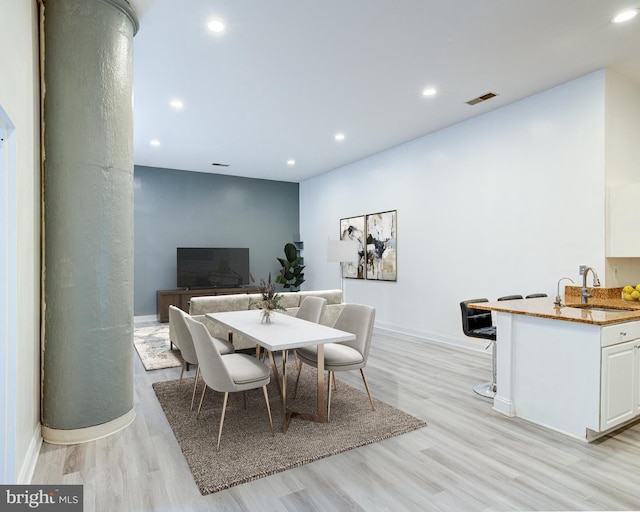 dining room featuring light hardwood / wood-style flooring, ornate columns, and sink