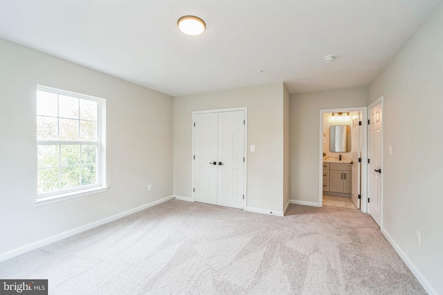 unfurnished bedroom featuring a closet, light colored carpet, and connected bathroom