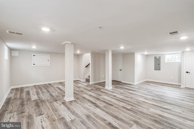 basement featuring electric panel and light hardwood / wood-style flooring