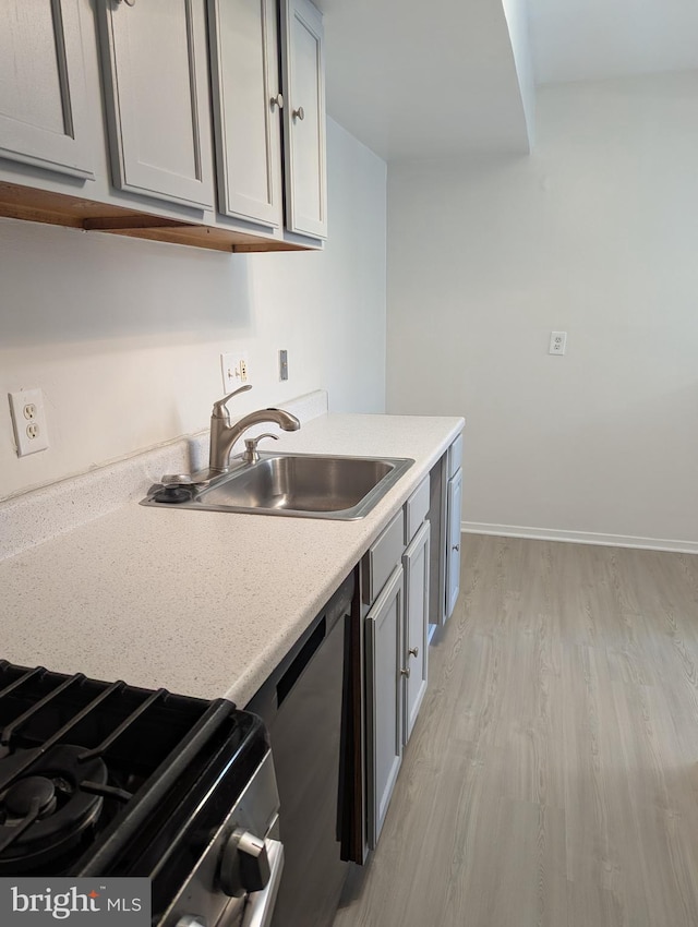 kitchen featuring stainless steel dishwasher, gray cabinetry, light wood-type flooring, and sink