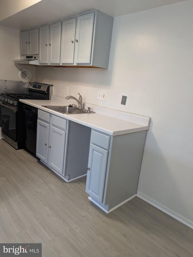 kitchen featuring gray cabinets, stainless steel range with gas cooktop, sink, and light hardwood / wood-style floors