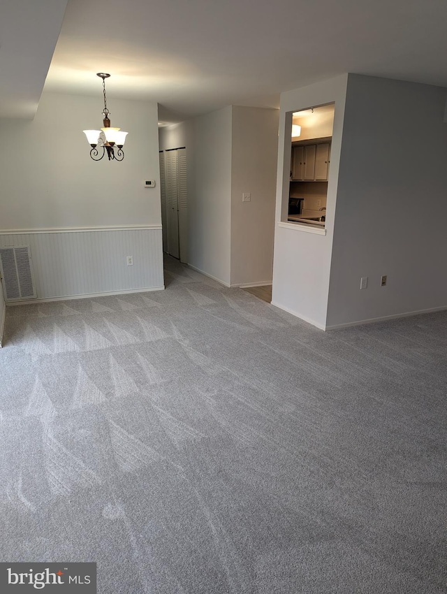 carpeted empty room featuring a chandelier