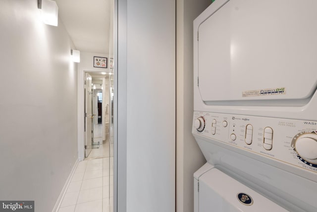 laundry area with stacked washer / dryer and light tile patterned flooring