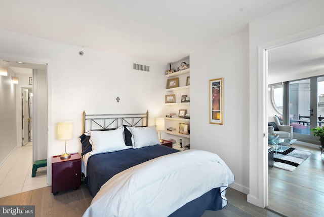 bedroom with french doors and hardwood / wood-style floors