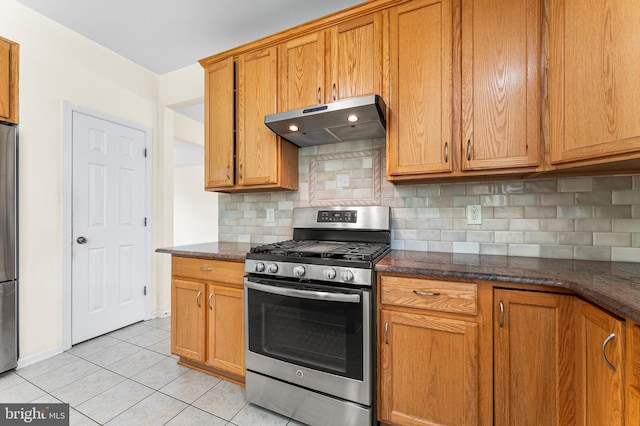 kitchen with decorative backsplash, stainless steel appliances, light tile patterned floors, and dark stone counters