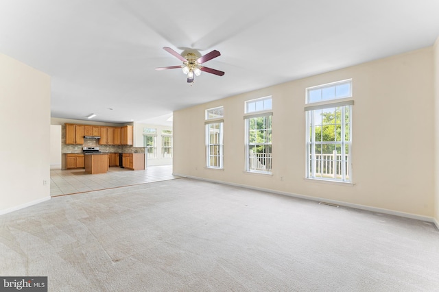 unfurnished living room with light carpet, ceiling fan, and a healthy amount of sunlight