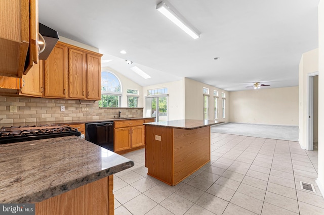 kitchen featuring ceiling fan, light tile patterned flooring, vaulted ceiling with skylight, dishwasher, and a center island