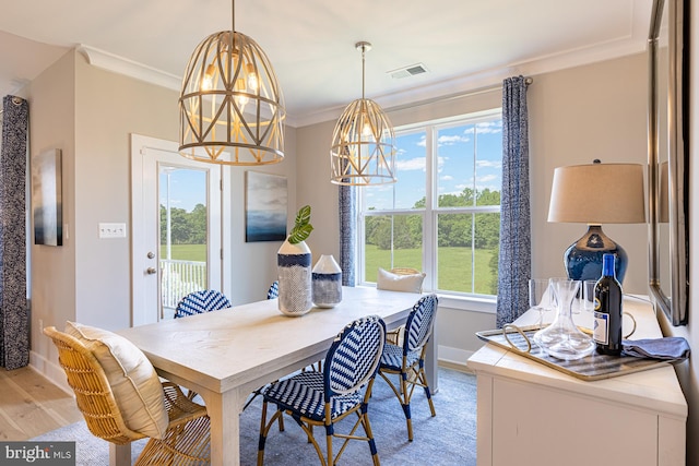 dining area featuring light wood-type flooring and crown molding