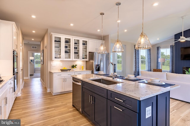 kitchen featuring sink, white cabinets, vaulted ceiling, appliances with stainless steel finishes, and decorative light fixtures