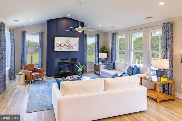 living room with ceiling fan, light hardwood / wood-style flooring, vaulted ceiling, and a large fireplace