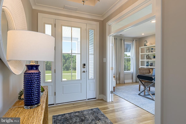 foyer with ornamental molding, light hardwood / wood-style floors, and a healthy amount of sunlight