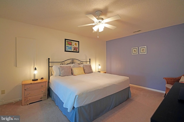 bedroom with ceiling fan, light carpet, and a textured ceiling