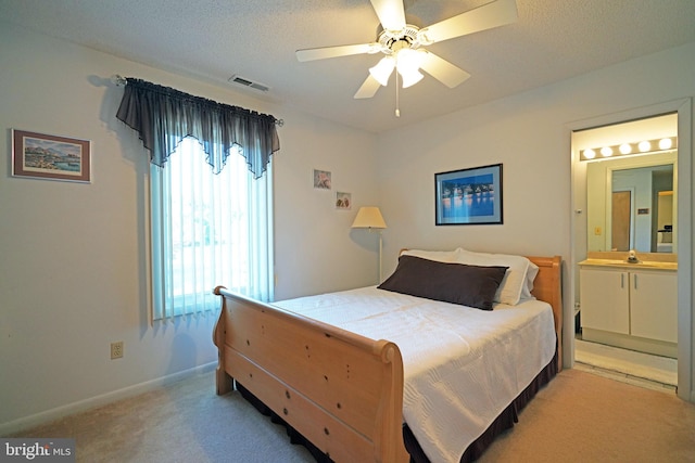 carpeted bedroom with ceiling fan, a textured ceiling, and ensuite bath