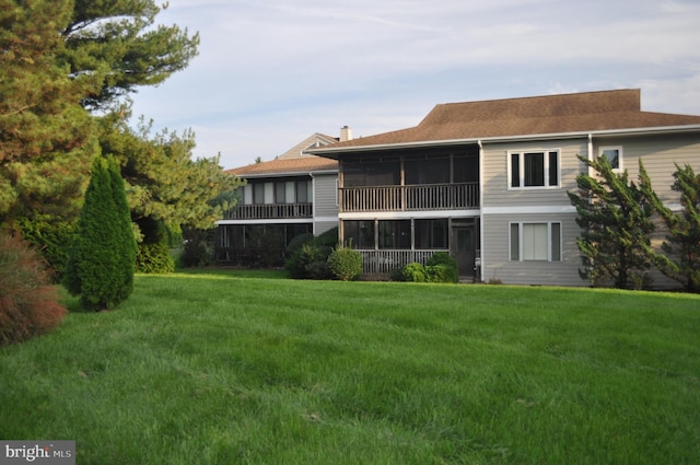 rear view of property with a lawn and a sunroom