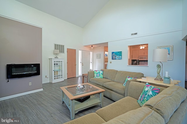 living room with sink, hardwood / wood-style floors, and high vaulted ceiling