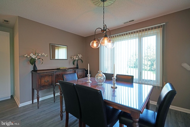 dining area with a textured ceiling and dark hardwood / wood-style flooring